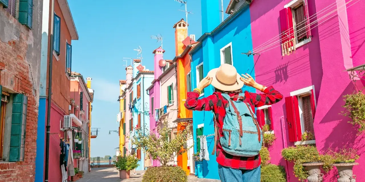 Una turista ammira le case colorate di Burano, un'isola raggiungibile con i traghetti da Chioggia.