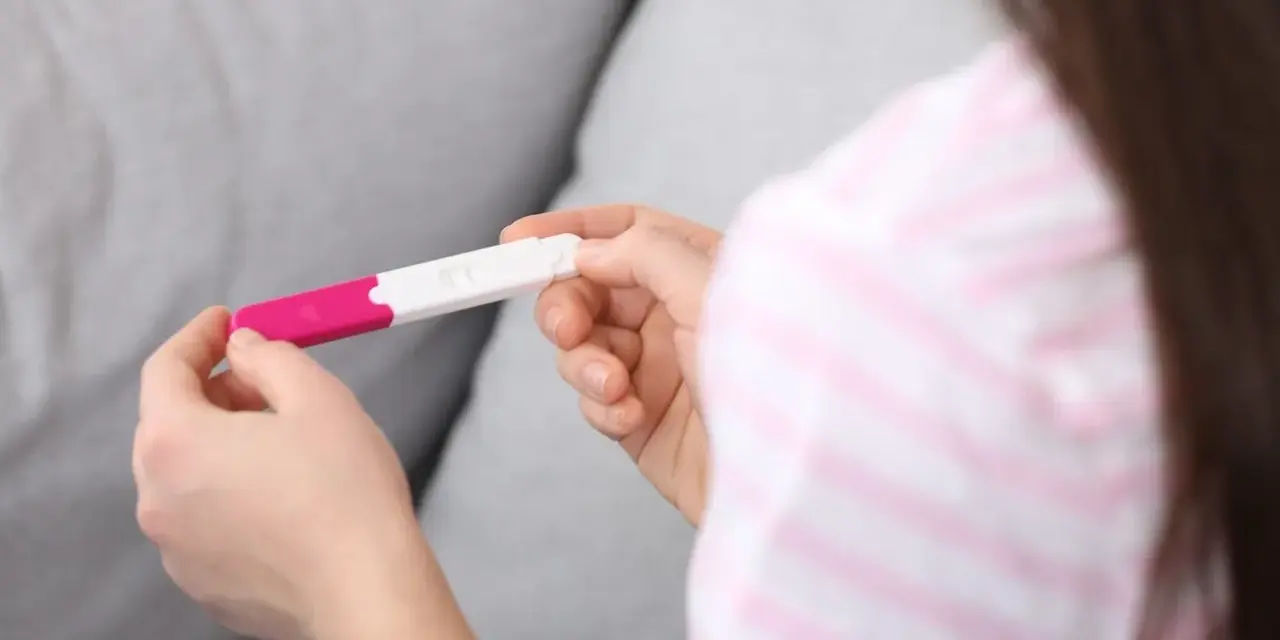 Dłonie trzymające test ciążowy. Wynik wskazuje na 1 miesiąc ciąży, co może być początkiem nowej, pięknej historii.