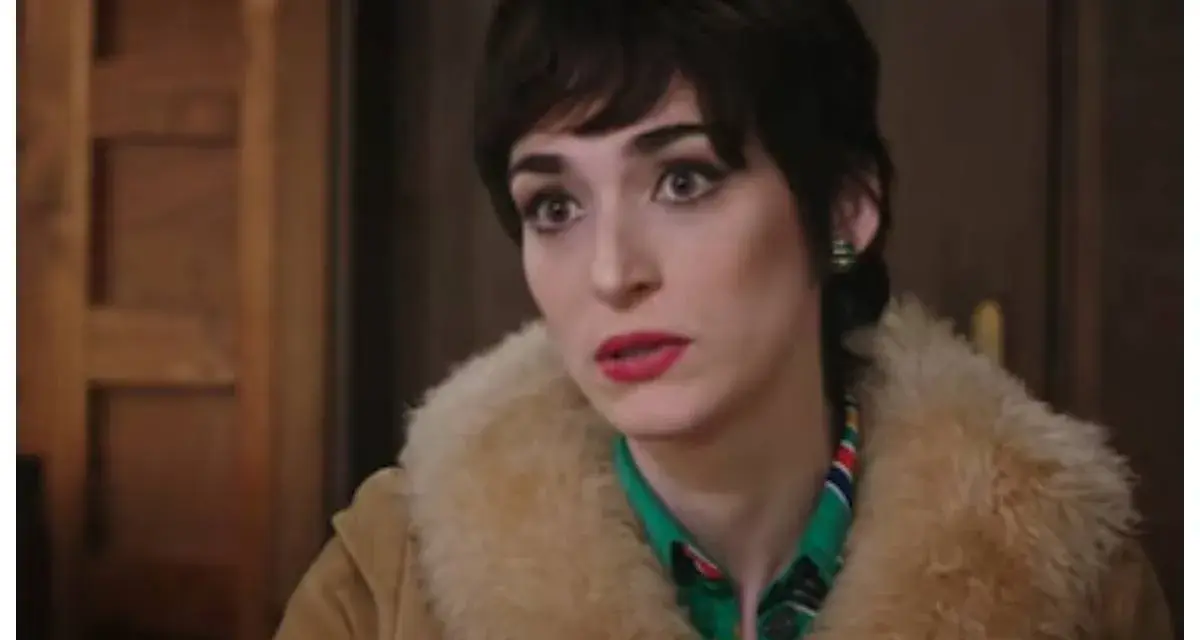 Una donna con un taglio di capelli corto e scuro, trucco marcato e un cappotto di pelliccia chiara. Le anticipazioni di Cuori 3 promettono colpi di scena.