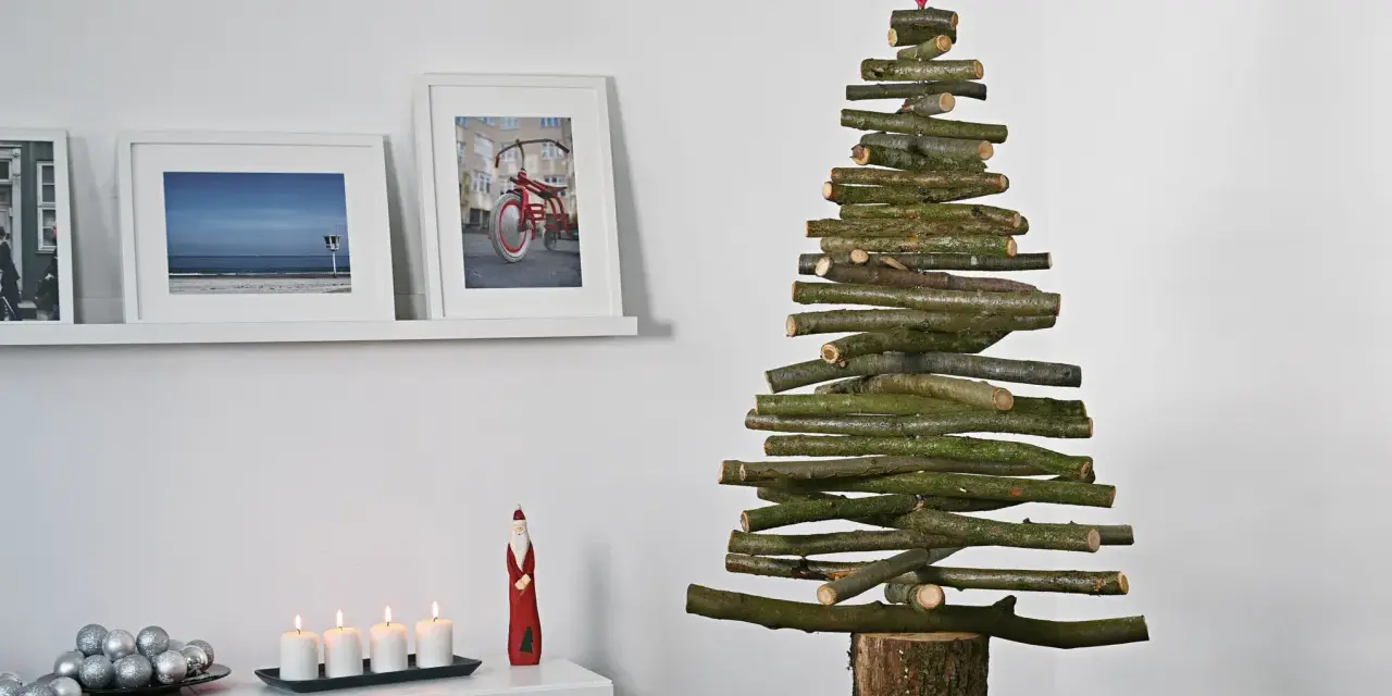 Ein rustikaler Tannenbaum aus Holzlatten, selbstgemacht, mit rotem Stern. Daneben Bilder und Kerzen.