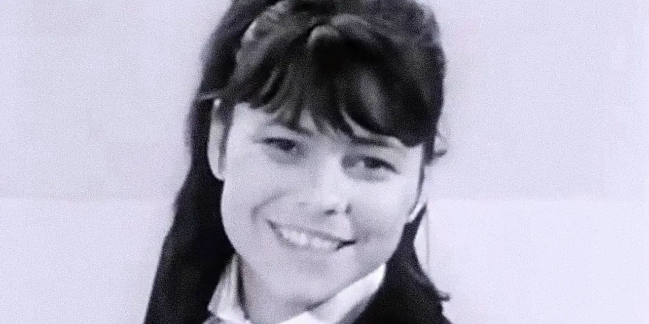 Uśmiechnięta Karin Stanek, jak malowana lala, w czarnym żakiecie i białej koszuli.