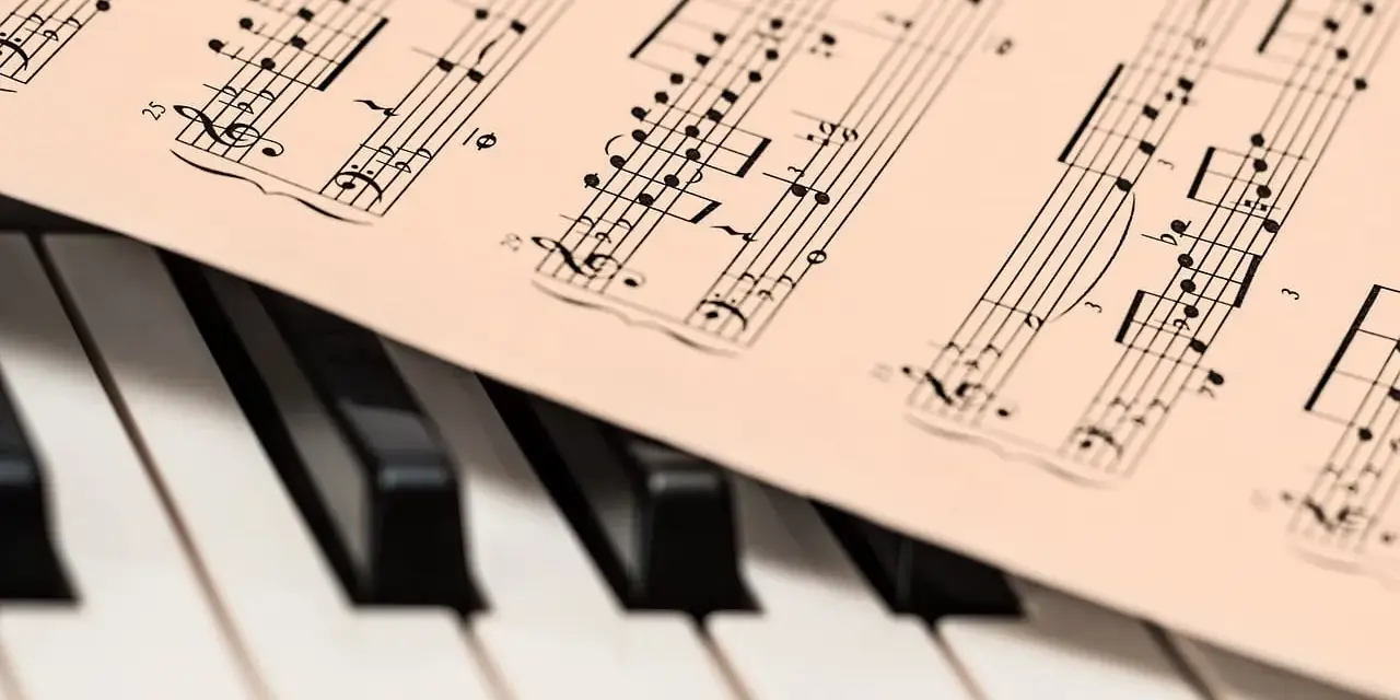 Partytura z nutami na klawiaturze pianina, gotowa do zagrania najsłynniejsze utwory jazzowe.