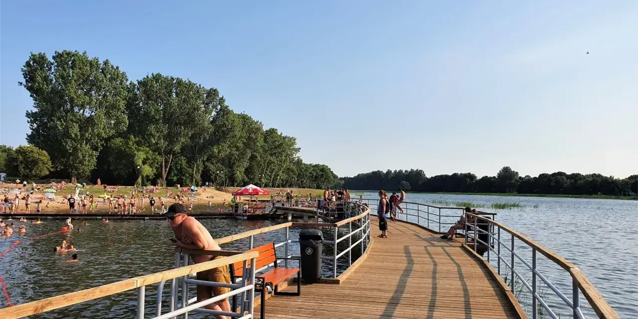Ludzie odpoczywają i kąpią się nad zalewem Borki. Drewniane molo zaprasza do spacerów i podziwiania widoków.