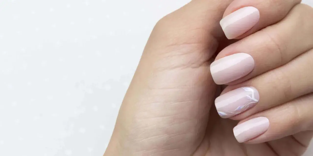 Main gauche avec des ongles pastel, dont un orné d'un motif floral délicat. Parfait pour faire les ongles.
