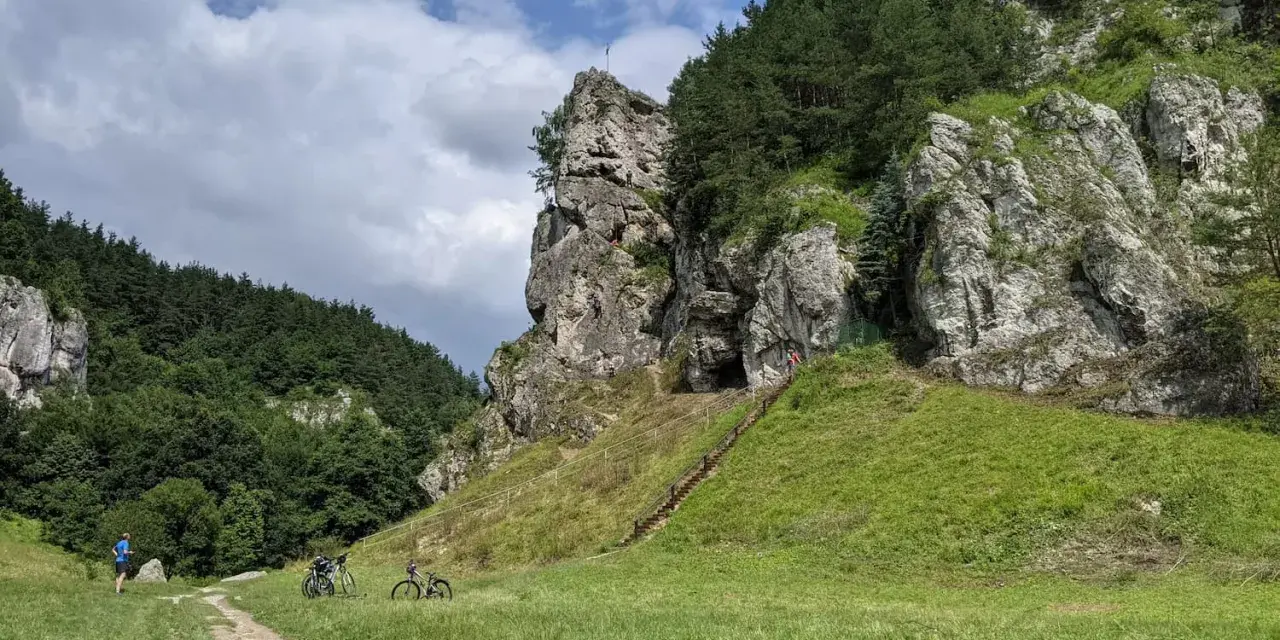 Dolina Kobylańska zachwyca skalnymi formacjami i zielonymi zboczami. Na ścieżce rowerzyści, a na skałach wspinacze.