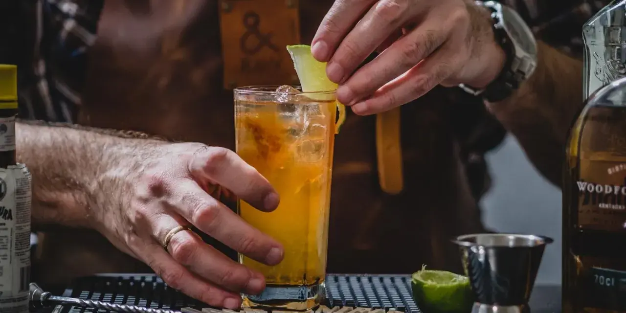 Barman kończy przygotowywać drinka na tequili, dodając plasterek limonki.