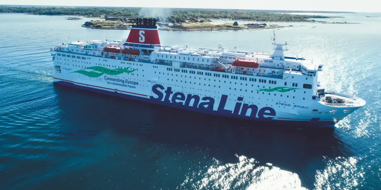 Stena Spirit, duży prom Stena Line, płynie po błękitnym morzu, z zielonymi liśćmi i napisem "Connecting.Europe" na burcie.