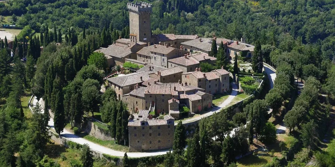 Il castello di Gargonza, un borgo medievale in pietra con torre, immerso nel verde della Toscana.
