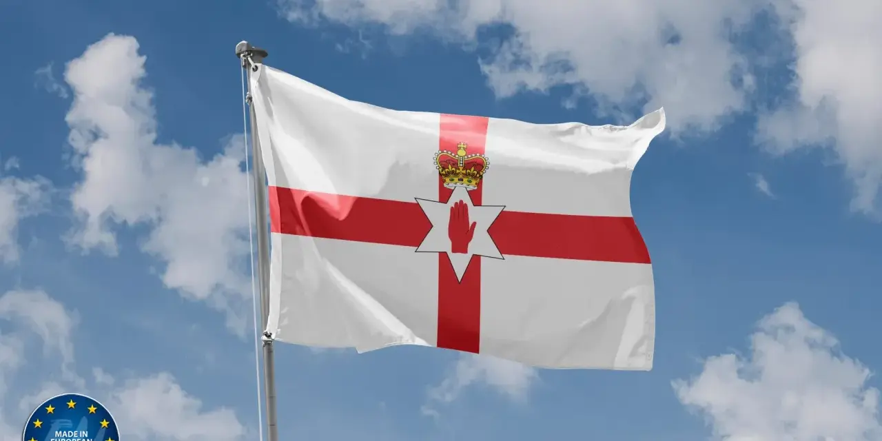 Flaga Irlandii Północnej powiewa na tle błękitnego nieba z chmurami. Symbolizuje historię i tożsamość regionu.
