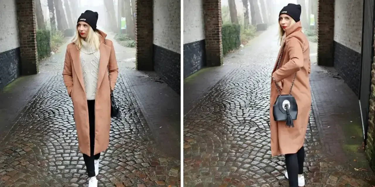 Kobieta w płaszczu w kolorze camel i czarnej czapce idzie brukowaną alejką.