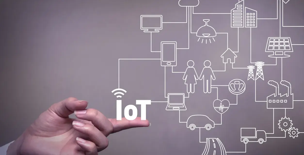A hand points to the word "IoT," illustrating the vast network of connected devices and systems that offer significant **iot benefits for business**, from smart homes to factories.