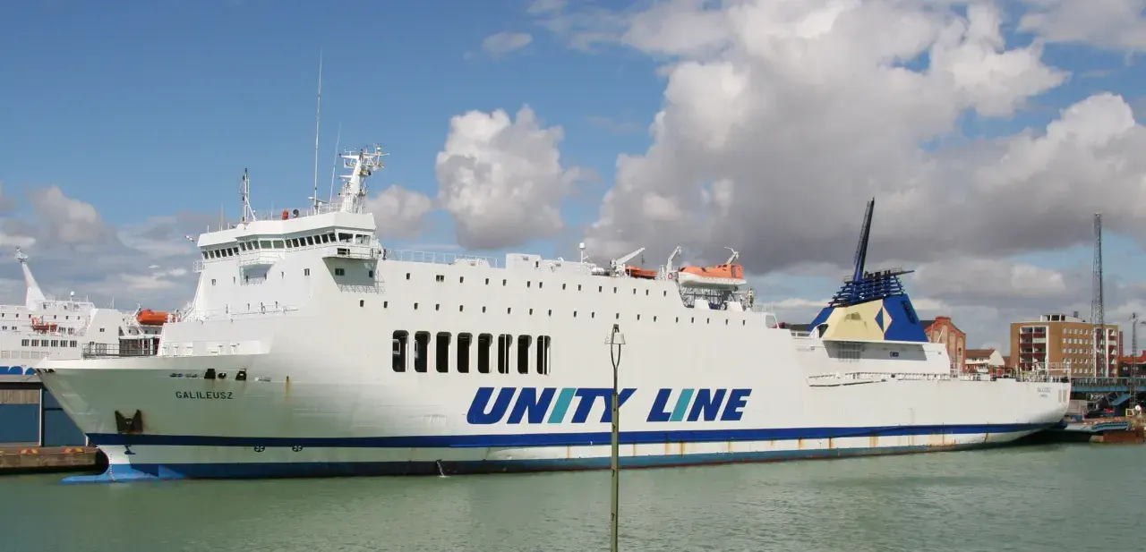 Biały prom Galileusz z napisem "UNITY LINE" cumuje w porcie.