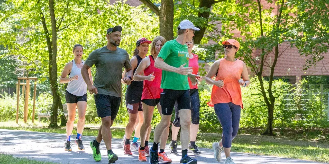Eine Gruppe von Läufern genießt eine gemeinsame Trainingseinheit in Berlin. Die Laufgruppen Berlin sind aktiv und motiviert.
