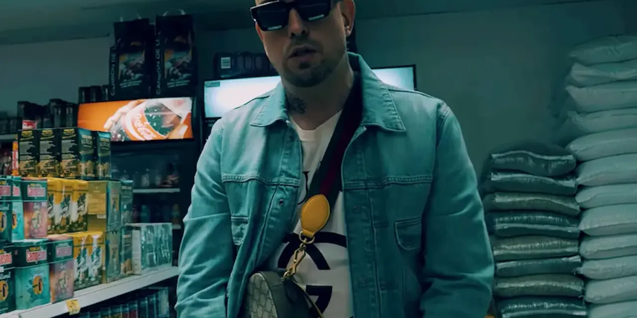 Sentino Malik w dżinsowej kurtce i okularach stoi w sklepie, otoczony towarem.