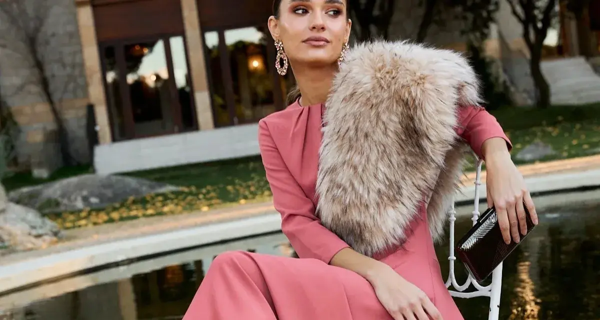 Elegante outfit fiesta invierno: vestido rosa palo, chal de pelo y bolso de mano.