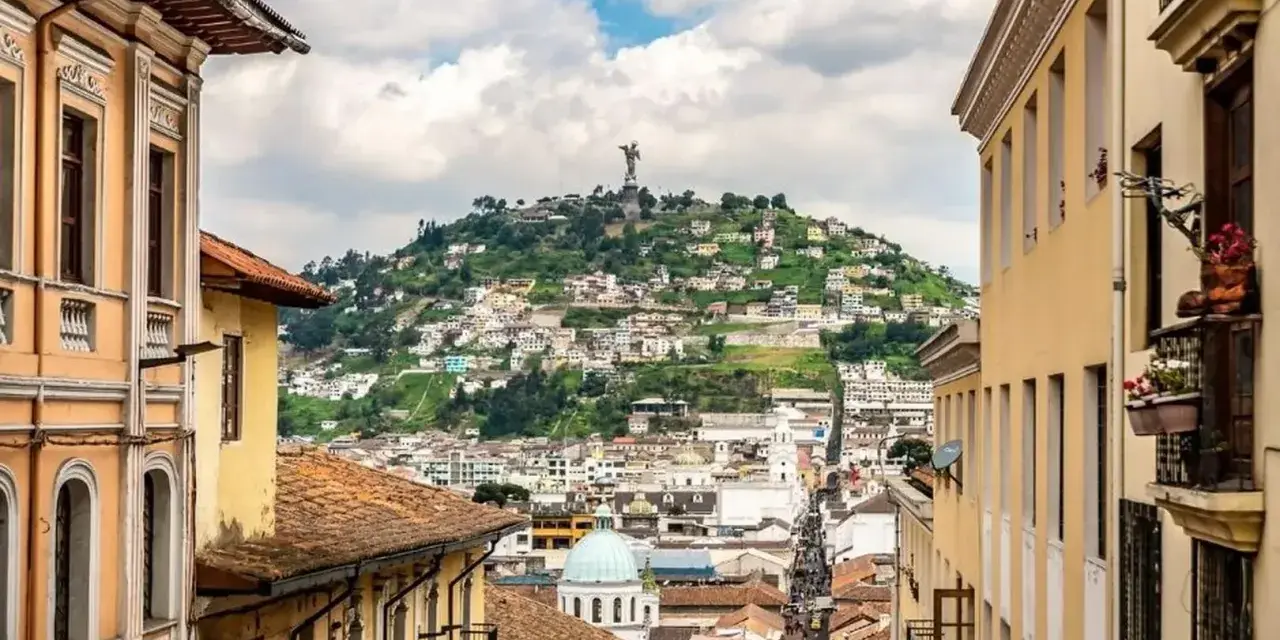 Widok na wzgórze z pomnikiem w Quito, stolicy Ekwadoru. Kolorowe budynki i wąskie uliczki tworzą malowniczy krajobraz.