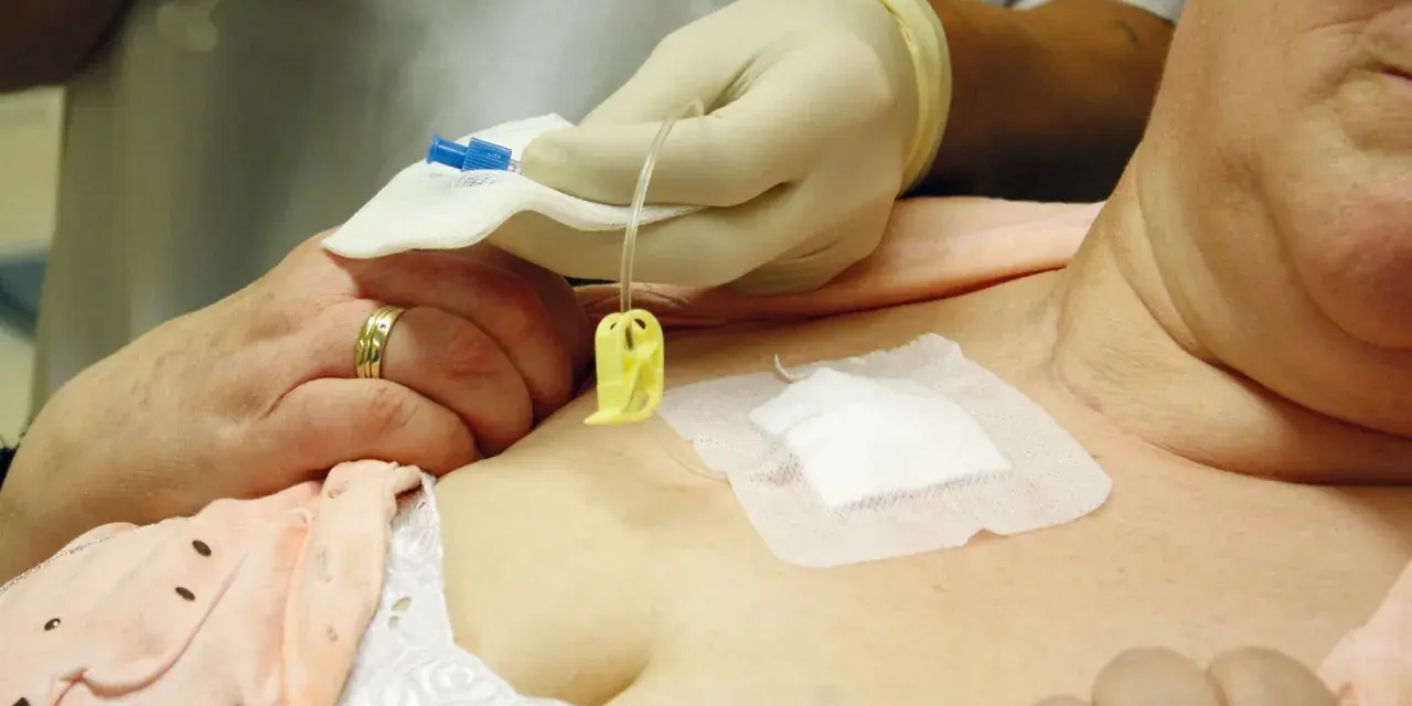 Eine Pflegekraft mit Handschuhen bereitet die Infusion an einem Port vene vor.