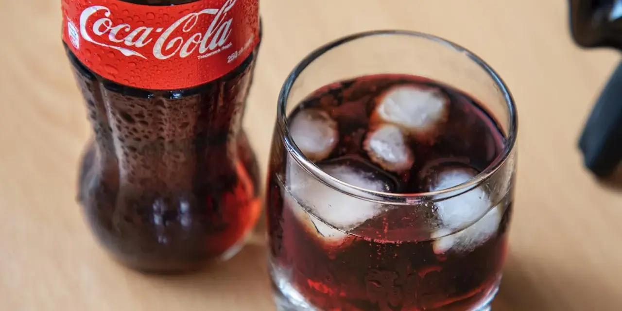 Szklanka z lodem i napojem, obok butelka Coca-Coli. Idealne na gorący dzień, gdy masz ochotę na wino z colą.