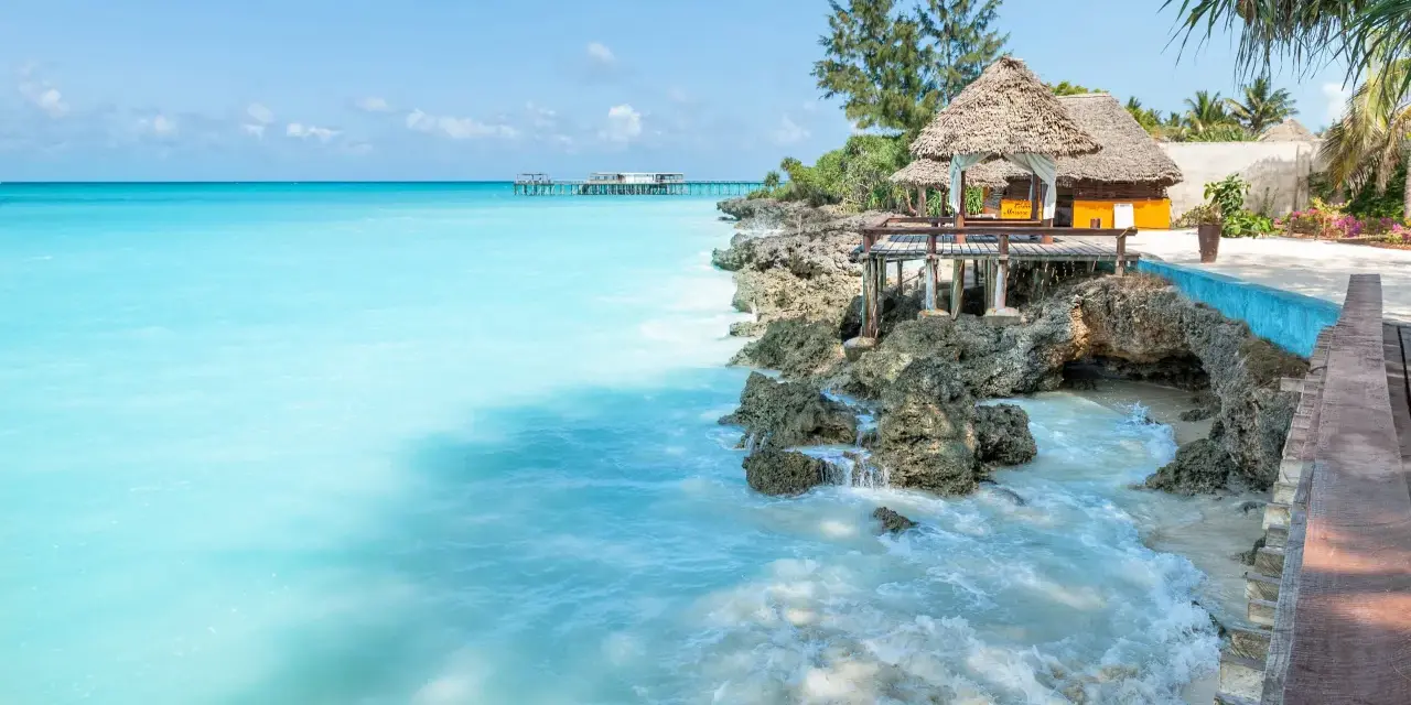 Turkusowe morze i tropikalna zabudowa na skale. Idealne miejsce na relaks, a zanzibar ceny mogą być zaskakująco przystępne.