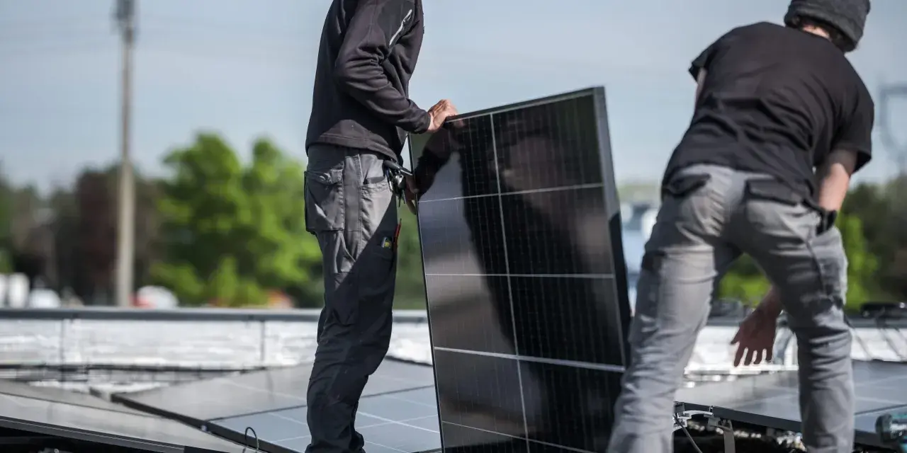 Pracownicy montują panele fotowoltaiczne, przygotowując zgłoszenie rozbudowy instalacji fotowoltaicznej PGE.