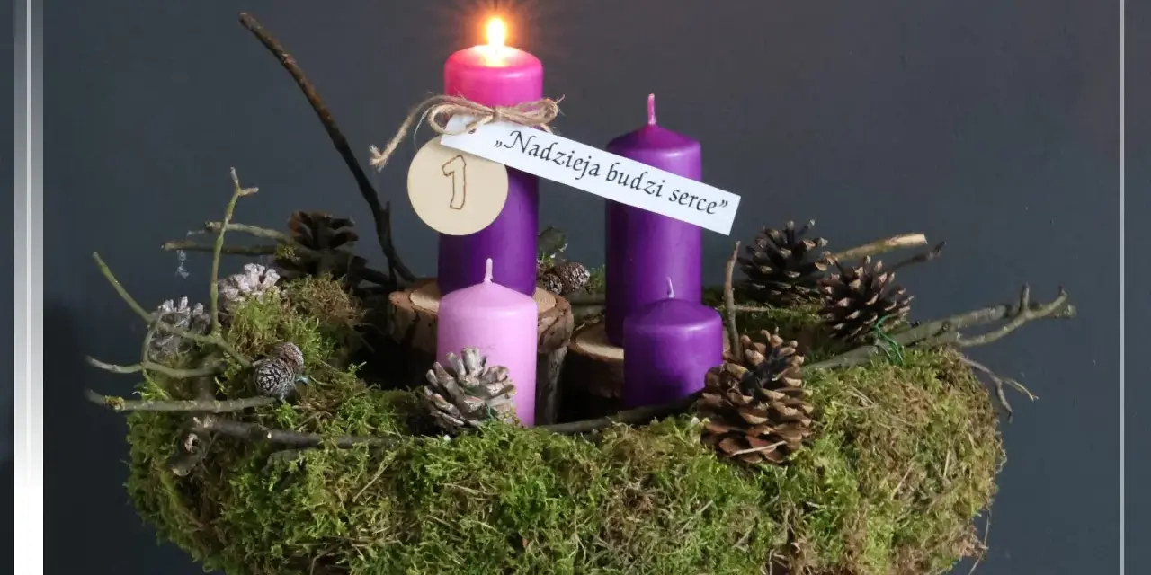 Wieniec adwentowy z zapaloną świecą, ozdobiony mchem, szyszkami i gałązkami. "Nadzieja budzi serce" - napis na pierwszej niedzieli adwentu.