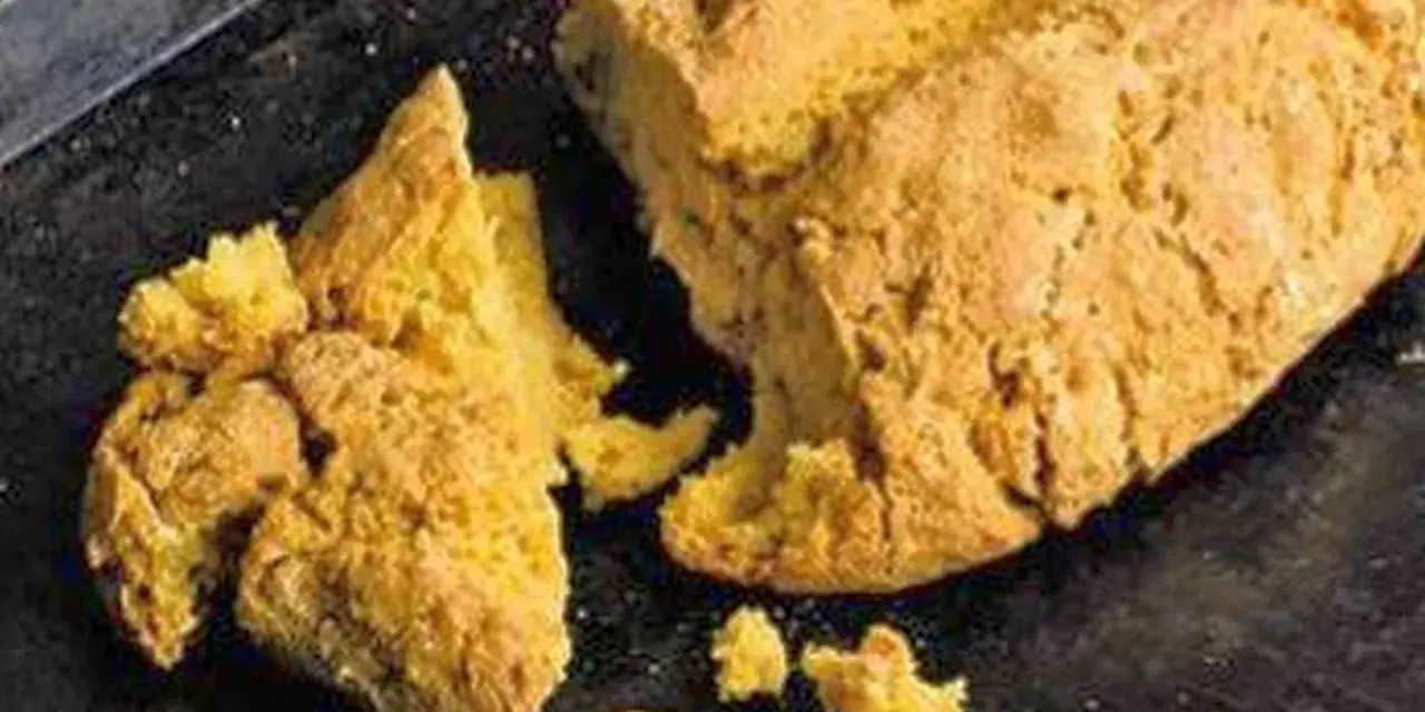 Goldgelbes, rustikales Brot, das nach Rezepten mit Lupinen aussieht, liegt auf einem dunklen Blech.