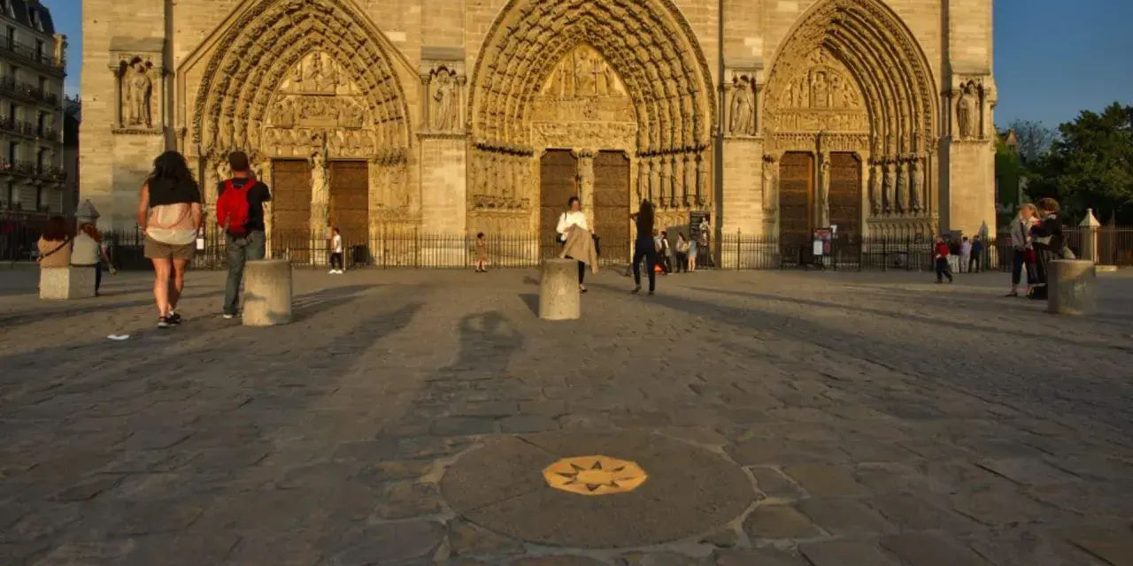 Devant Notre-Dame, le point zéro altitude marque le centre de Paris. Des visiteurs admirent la façade.