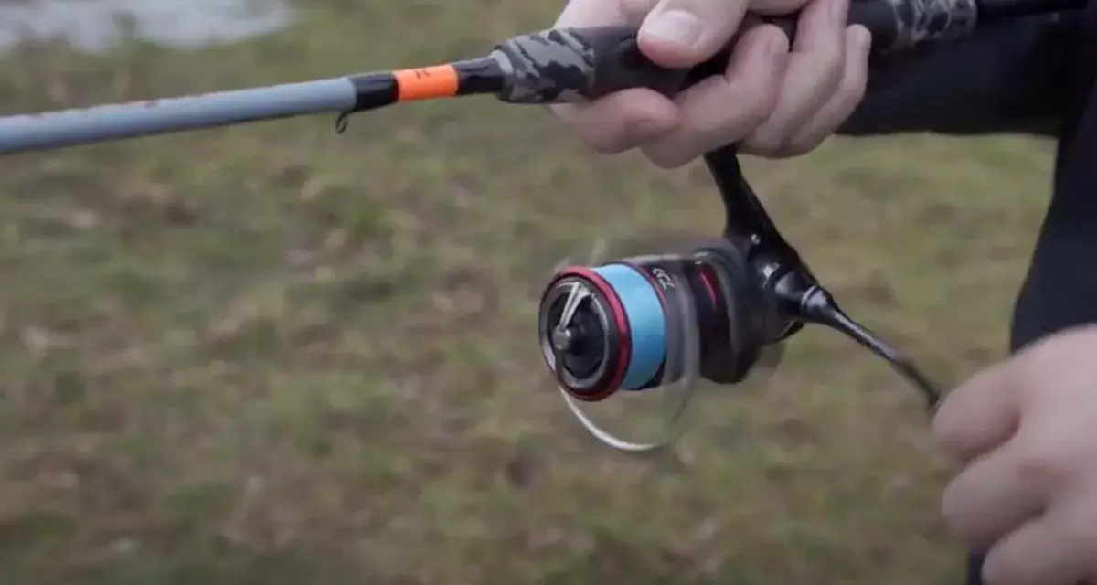 Daiwa Fuego Camo Spin Test: Eine Hand hält eine Angelrute mit Camo-Griff und einer Rolle mit blauer Schnur.