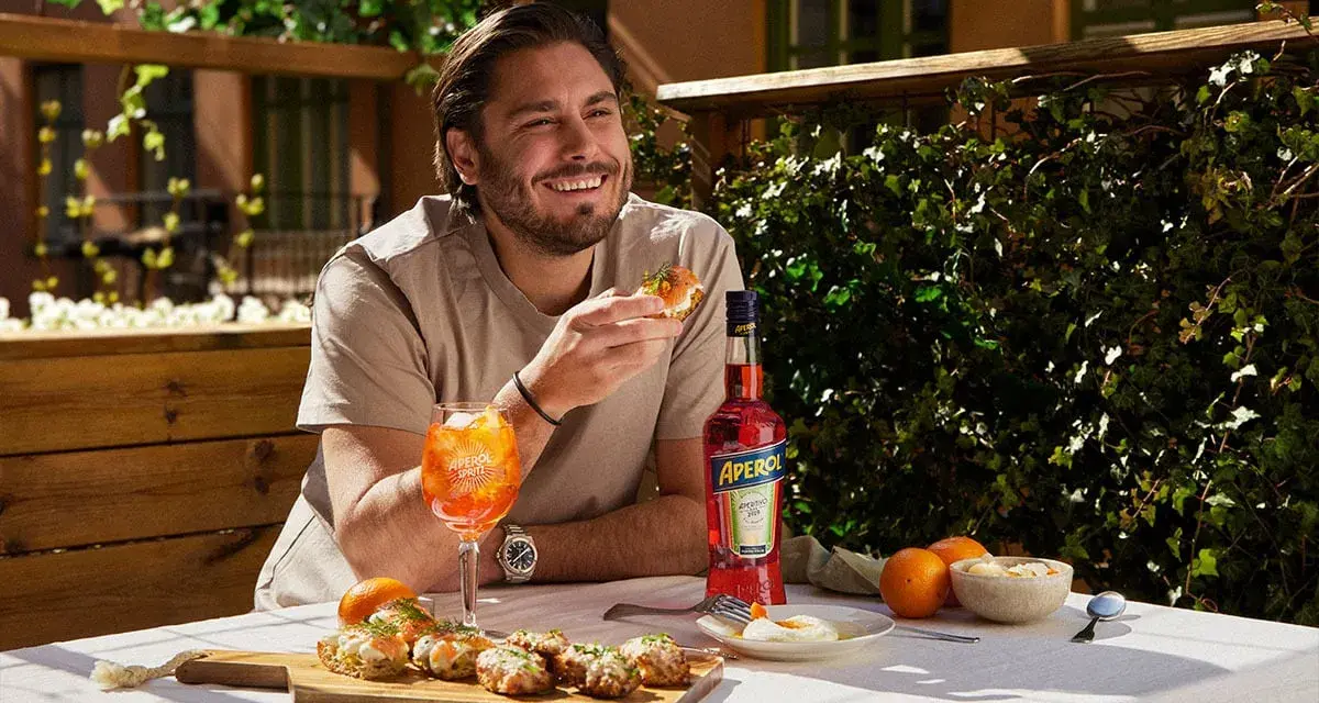 Man njuter av en Aperol Spritz och tilltugg på en solig uteservering.