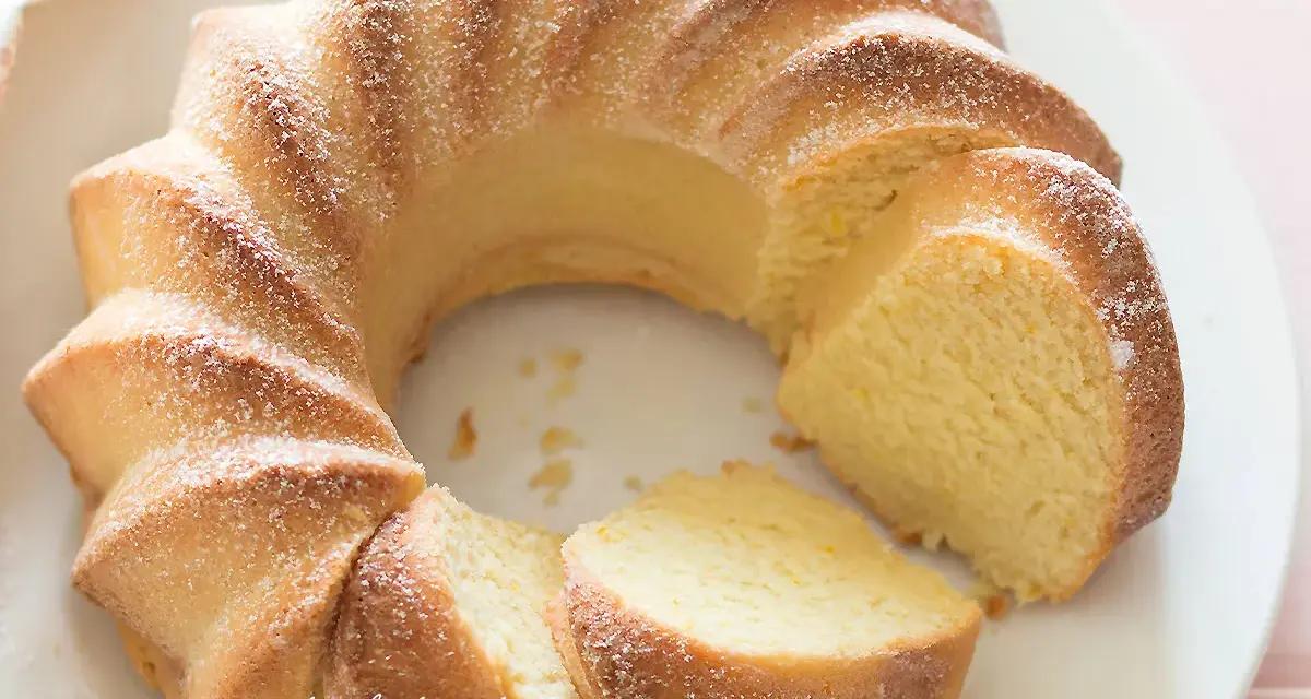 Una soffice torta di ricotta, spolverata di zucchero a velo, con una fetta tagliata.