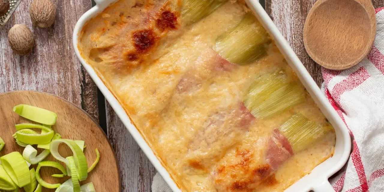 Gratin de poireaux au jambon, doré et crémeux, prêt à être dégusté. Une recette réconfortante.