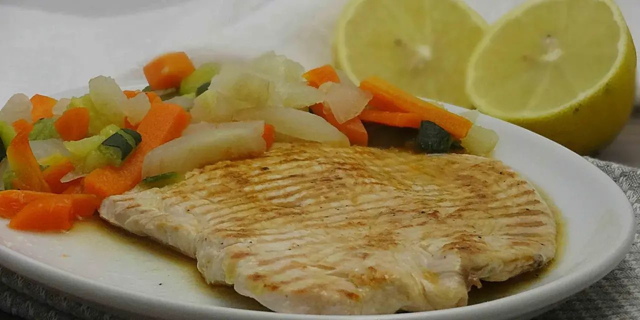 Fettine di tacchino appetitose, cotte alla griglia, servite con verdure miste e spicchi di limone.