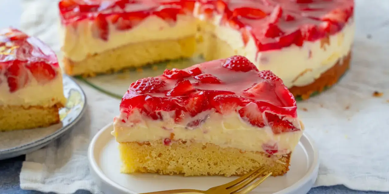 Ein saftiger Erdbeer Schmand Kuchen mit frischen Erdbeeren und rotem Tortenguss, ein Stück auf einem Teller mit einer goldenen Gabel.