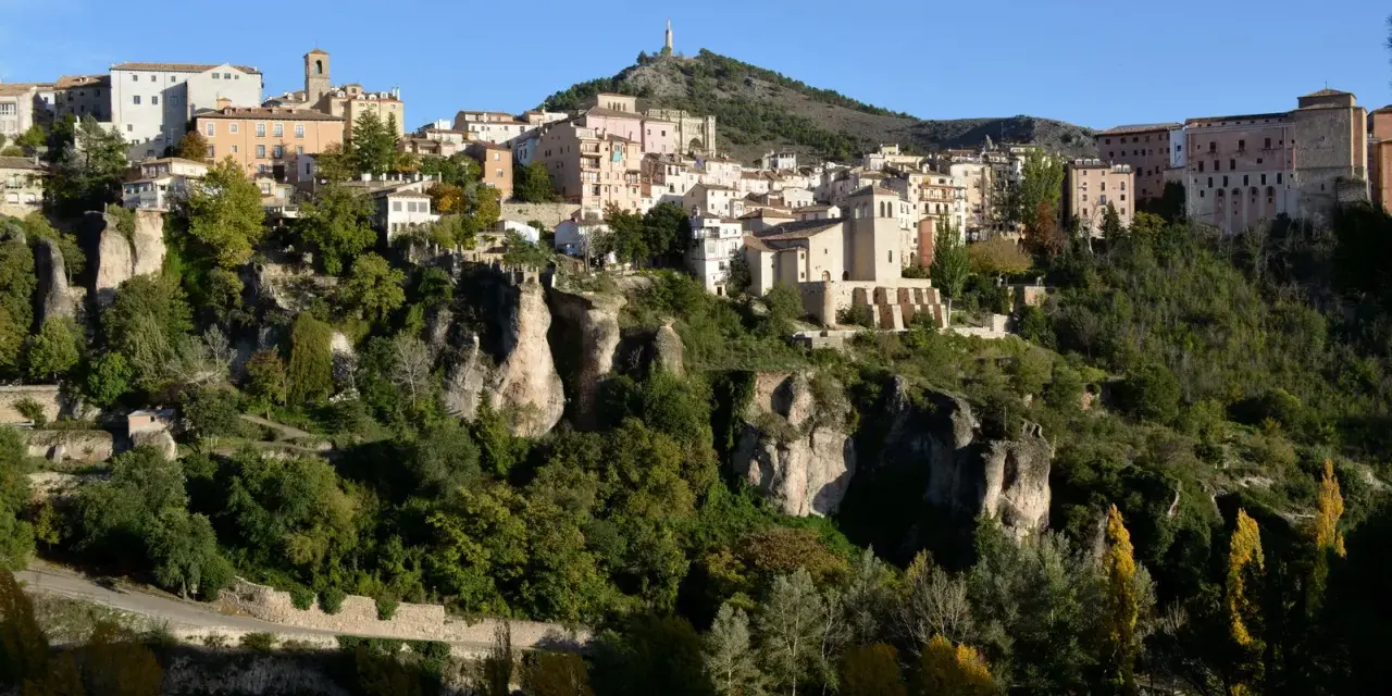 La ruta San Julián el Tranquilo en Cuenca: casas colgadas sobre riscos, vegetación frondosa y un cielo azul.