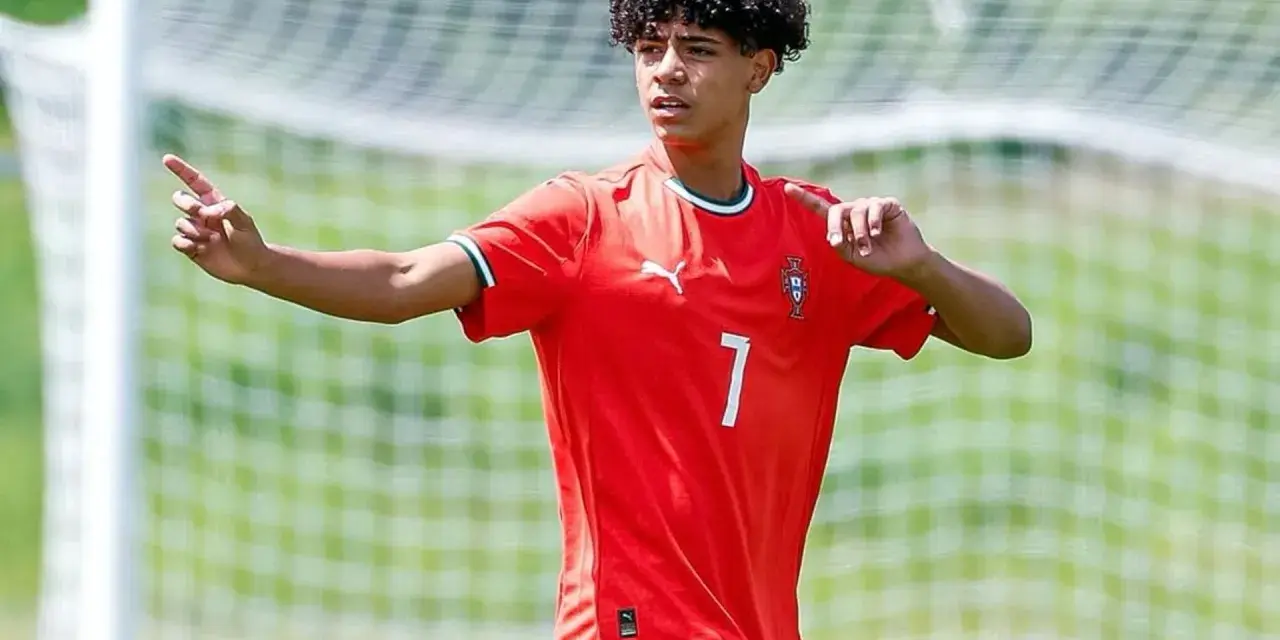 Cristiano Ronaldo Jr. con pelo rizado y camiseta roja con el número 7, señalando con el dedo índice.