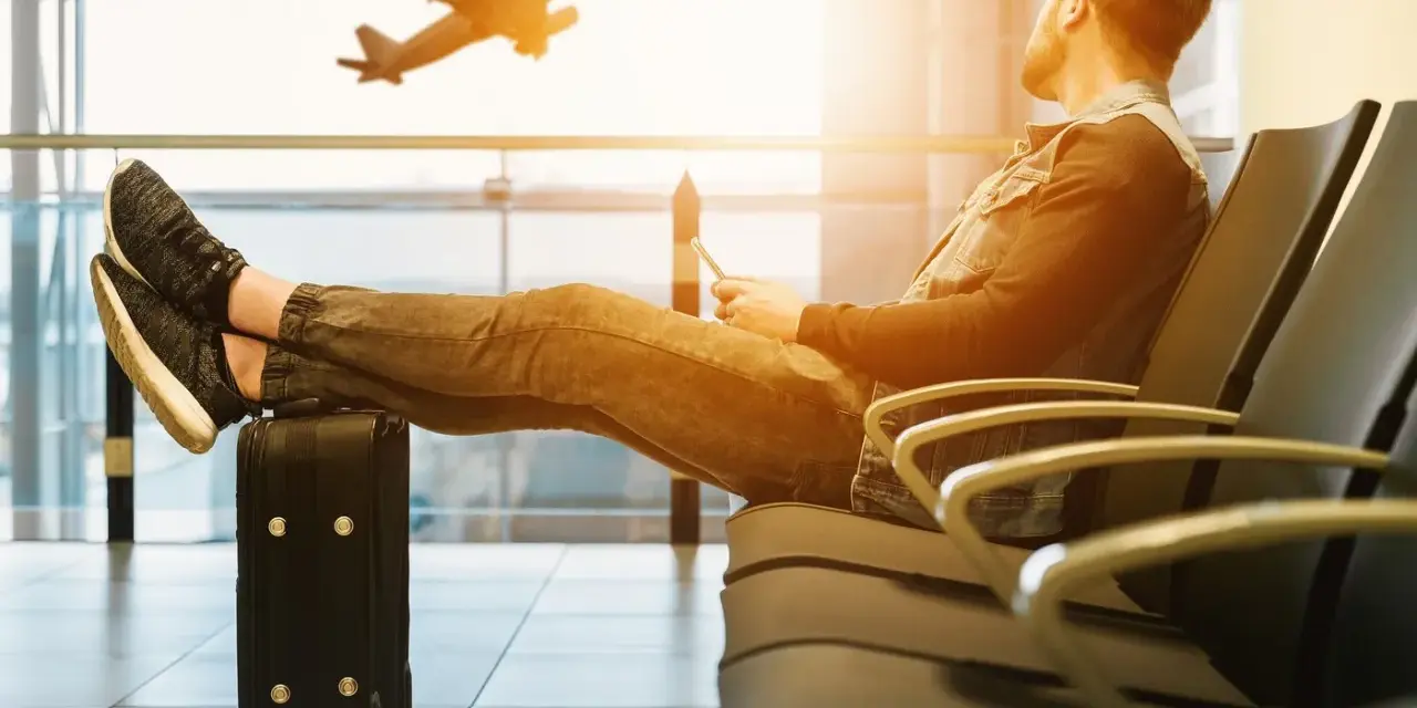 Mężczyzna czeka na lotnisku, nogi na walizce, samolot Wizzair startuje. Czyżby overbooking?
