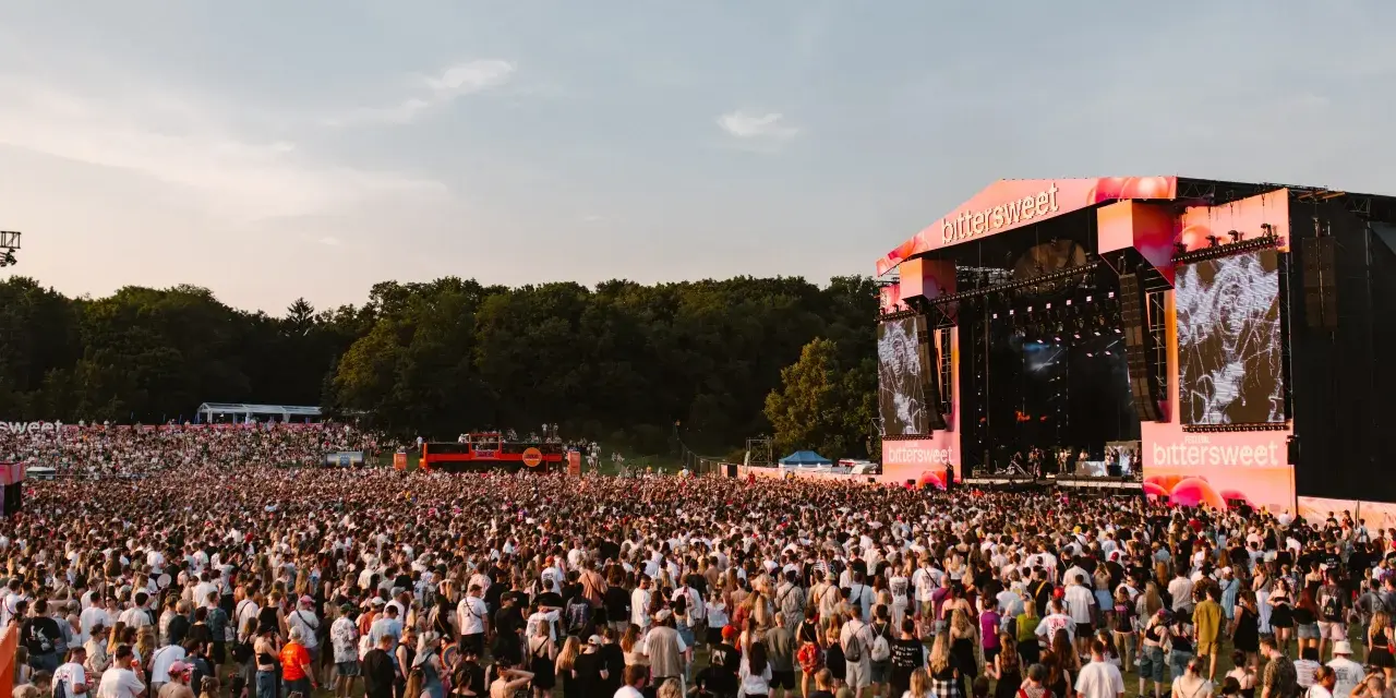 Tłum ludzi na festiwalu Bittersweet 2026, podziwiający scenę z wielkim ekranem i artystami. Słońce zachodzi, tworząc ciepłą atmosferę.