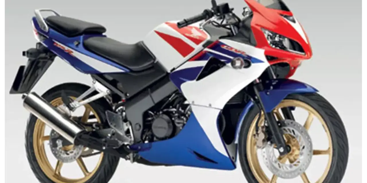 Sportowy motocykl Honda CBR 125R w barwach V-Max, z czerwonym, białym i niebieskim malowaniem.