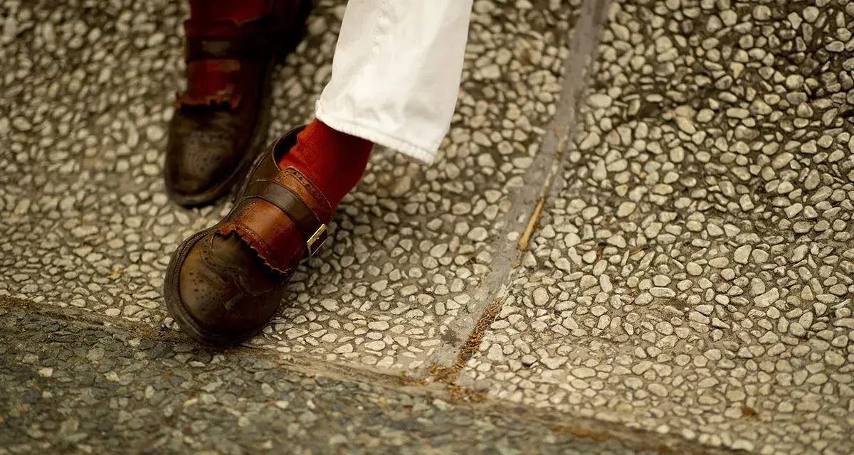 Scarpe marroni uomo con fibbia e calzini rossi, perfette per un look casual chic.