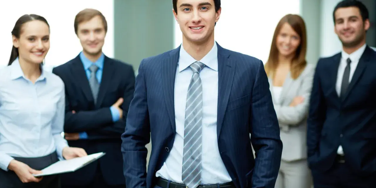 Equipo profesional sonriendo. Un ejemplo de como ir vestida a una entrevista de trabajo: traje oscuro, camisa clara y corbata.