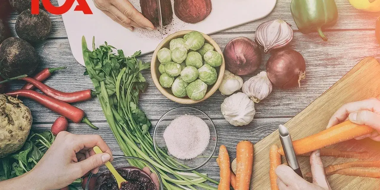 ICA-logotypen över en bild av färska grönsaker som förbereds för ett recept. Rödbetor skivas, morötter skalas och en skål med puré.