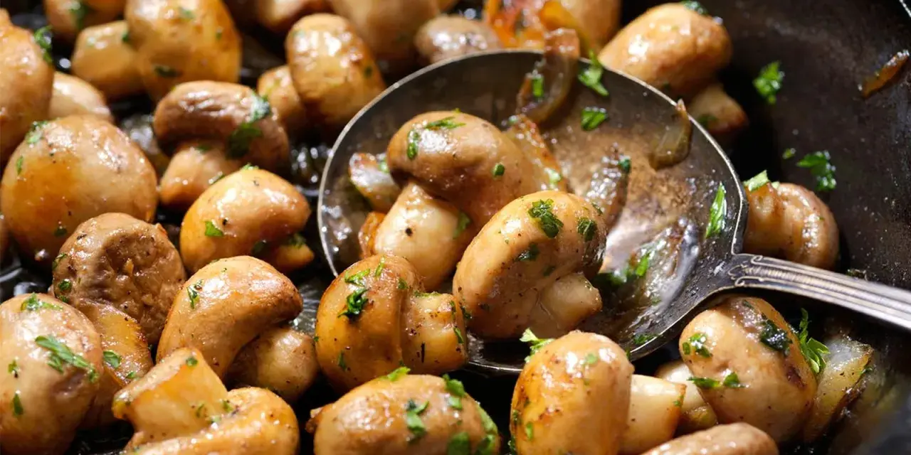 Champiñones salteados con perejil, perfectos para tus recetas con champiñones. Una cuchara sirve para probarlos.
