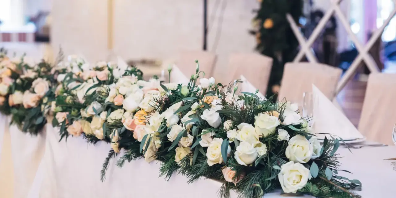 Eleganckie kwiaty na wesele zdobią stół, tworząc romantyczną atmosferę. Bukiet z róż i zieleni.