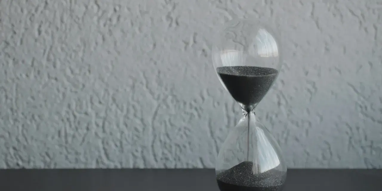 Clessidra con sabbia nera che scorre, simbolo del tempo che passa. Quanto tempo portare il lutto? Il tempo guarisce, ma il ricordo resta.