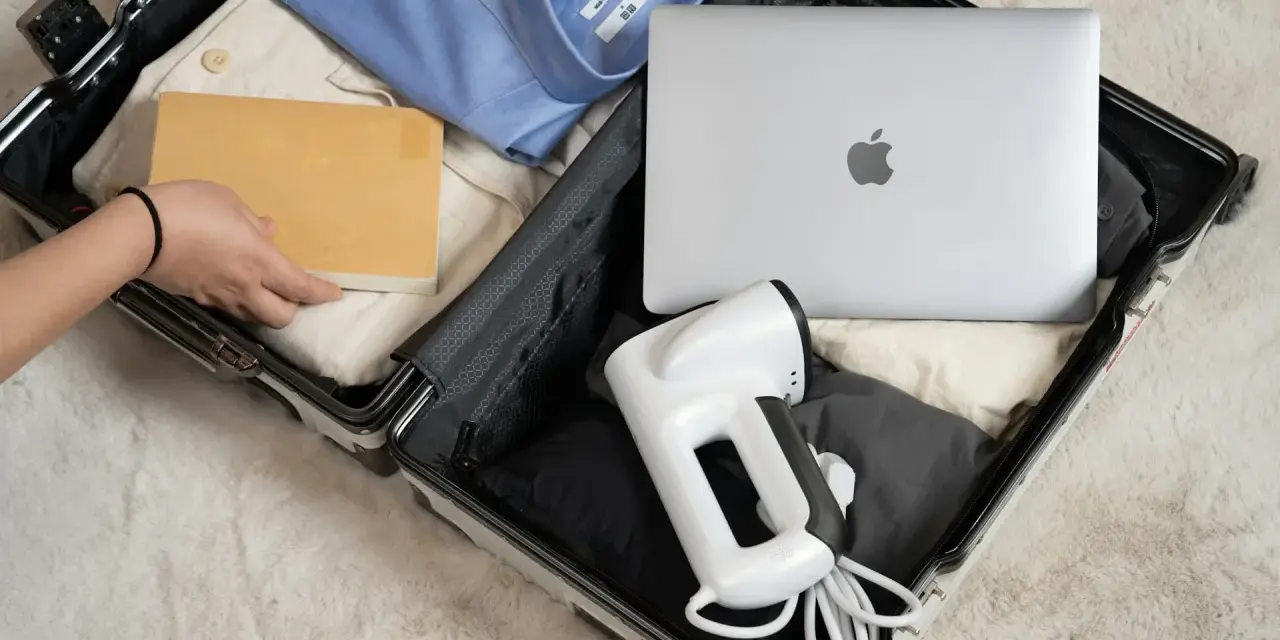 Pakowanie elektroniki w bagażu rejestrowanym: laptop, parownica do ubrań i książka.