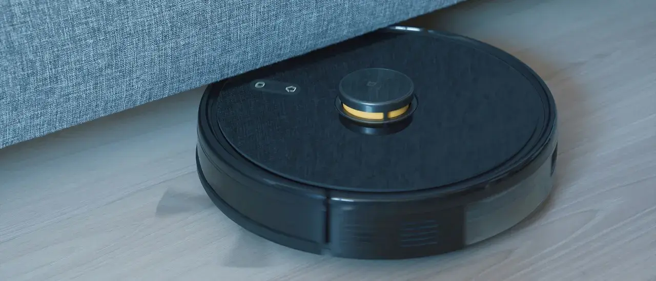 En robotdammsugare navigerar under en soffa, visar hur fungerar en robotdammsugare.