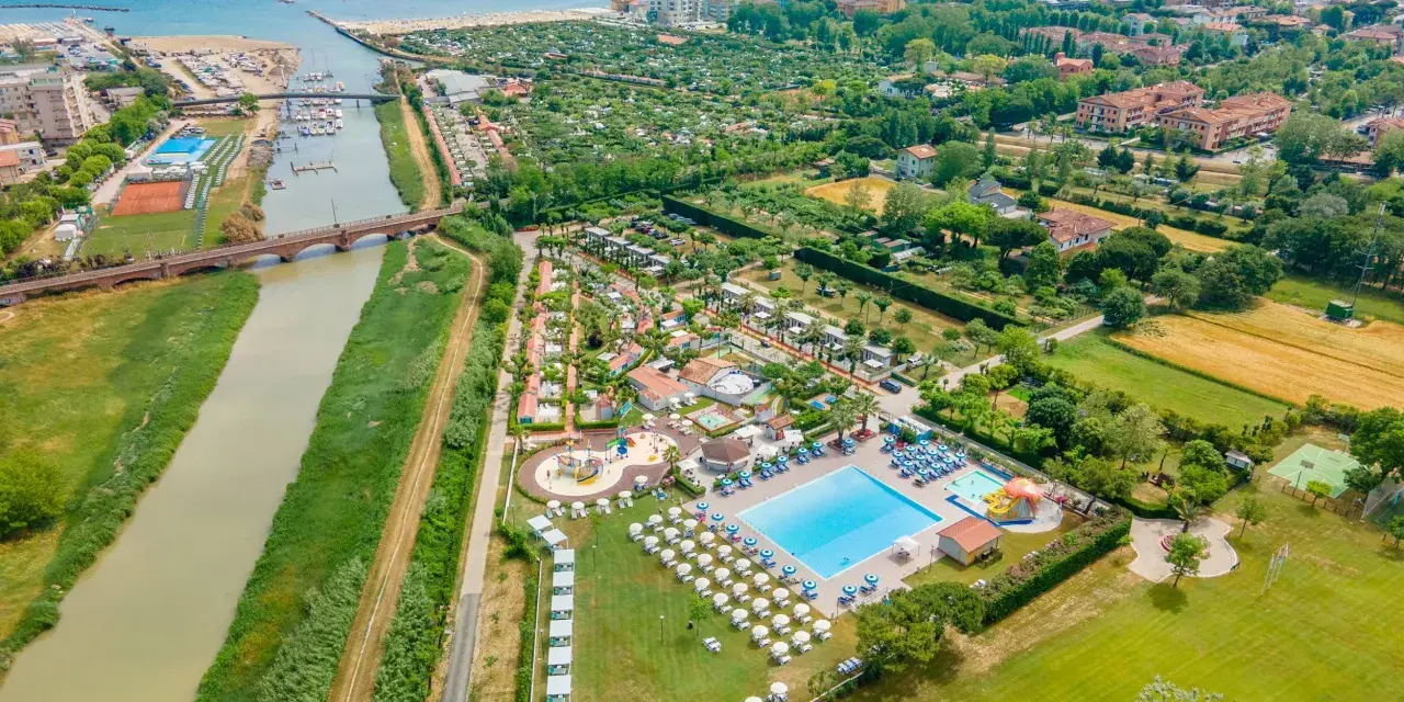 Widok z lotu ptaka na ośrodek campingowy Rubicone z basenami, leżakami, kortami tenisowymi i rzeką w pobliżu morza.