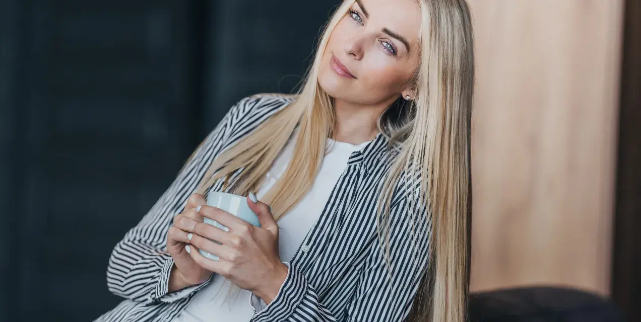 Blondynka z kubkiem w dłoniach, zamyślona, chce być sama.