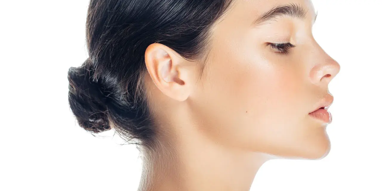 Profilo di donna con trucco leggero, evidenziato il contouring naso per un effetto scolpito. Pelle luminosa e capelli raccolti.