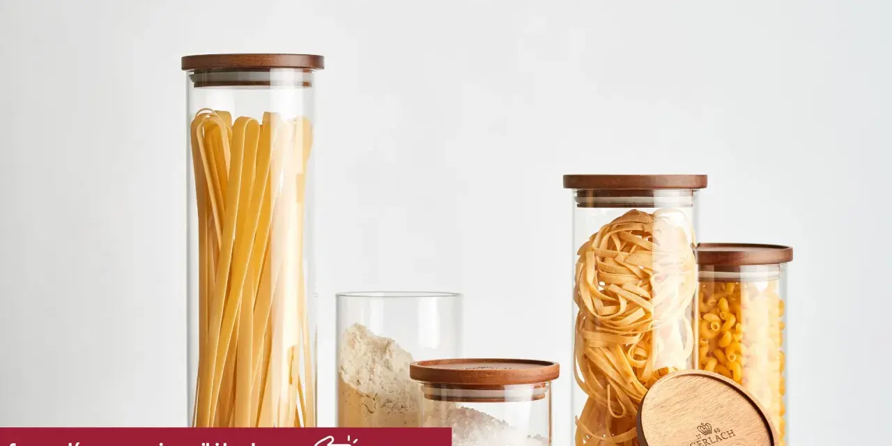 Szklane pojemniki z drewnianymi pokrywkami prezentują makaron świeży z lodówki kontra suchy z paczki: tagliatelle, fusilli i długie wstążki.